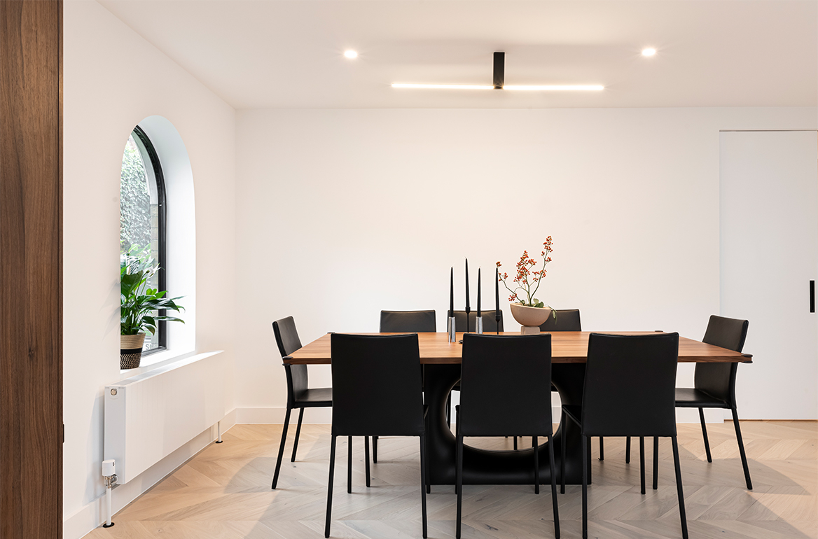 Quiet Luxury open plan dining room setting with black leather dining chairs, B&B Italia dining table with black leather leg to centre and minimal ceiling light curated by luxury interior design studio in london misch_MISCH studio